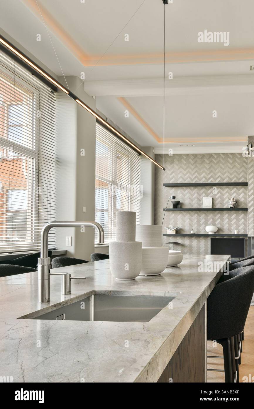 Eine elegante und stilvolle Küche mit moderner Beleuchtung, eleganten Möbeln und minimalistischer Ästhetik. Das Design bietet eine harmonische Mischung aus Funktionalität und Schönheit. Stockfoto