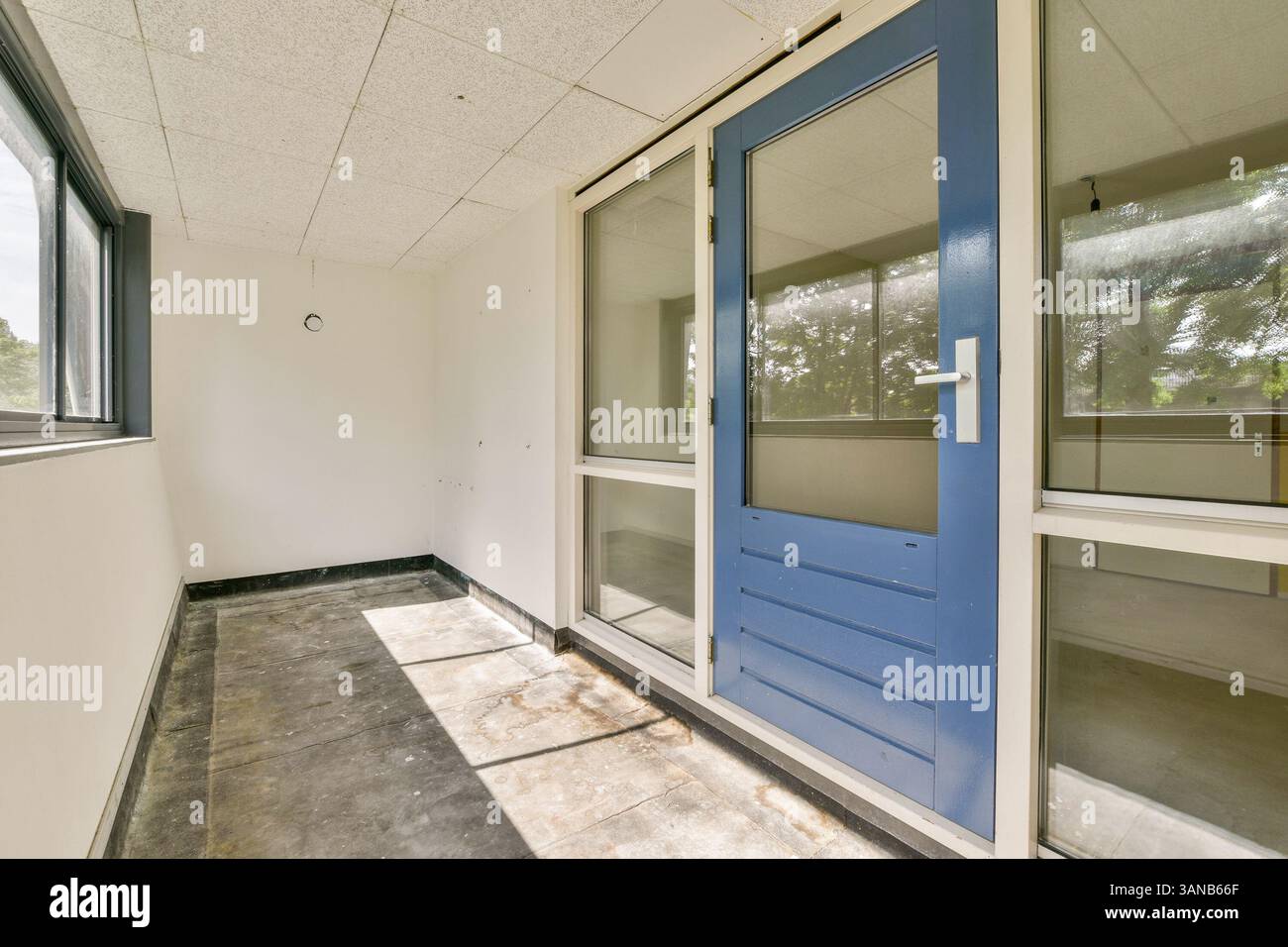 Ein moderner Innenbereich mit blauer Tür und großen Fenstern. Die neutralen Wände und Böden schaffen eine einladende Atmosphäre, die sich ideal für verschiedene Anwendungen eignet. Stockfoto
