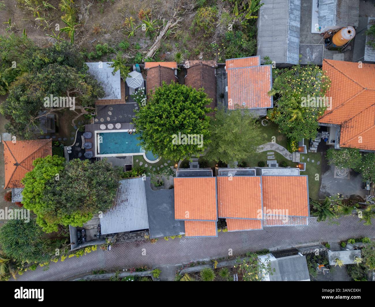 Blick aus der Vogelperspektive auf luxuriöse Villen und einen Swimmingpool, umgeben von tropischem Grün und Bäumen, Kuta Selatan, Indonesien. Stockfoto