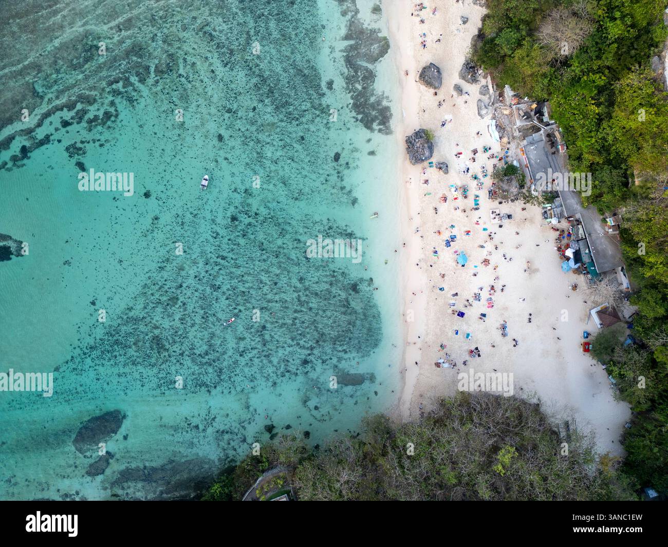 Aus der Vogelperspektive auf die Menschen, die den wunderschönen Strand mit türkisfarbenem Wasser und einem Boot auf dem Meer genießen, Kuta Selatan, Indonesien. Stockfoto