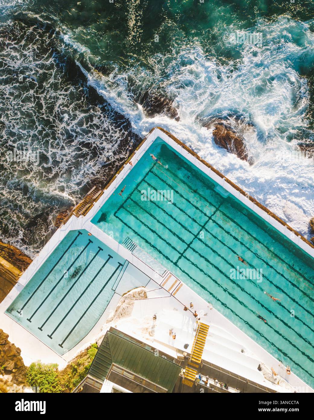 Blick aus der Vogelperspektive auf den Bondi Icebergs Swimming Club mit wunderschönen Meereswellen und pulsierender Küste, Sydney, Australien. Stockfoto