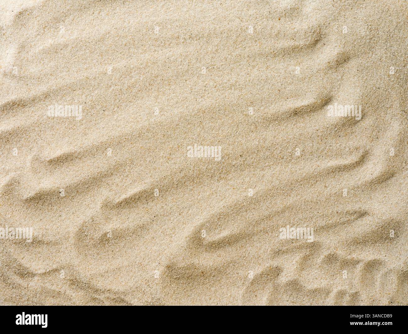 Strand Sandhintergrund mit natürlichem Wellenmuster. Sommer Hintergrund von Strandsand mit kleinen Steinen entlang der Ränder. Tourismus, Urlaub und Urlaub Stockfoto