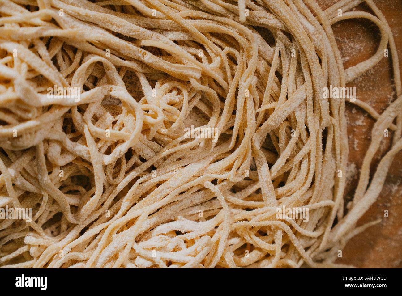 Eine Nahaufnahme langer Nudelnudeln mit einer körnigen Textur. Die Nudeln stapeln sich übereinander, wodurch ein Gefühl von Tiefe und Dimension entsteht. Das Bild Stockfoto