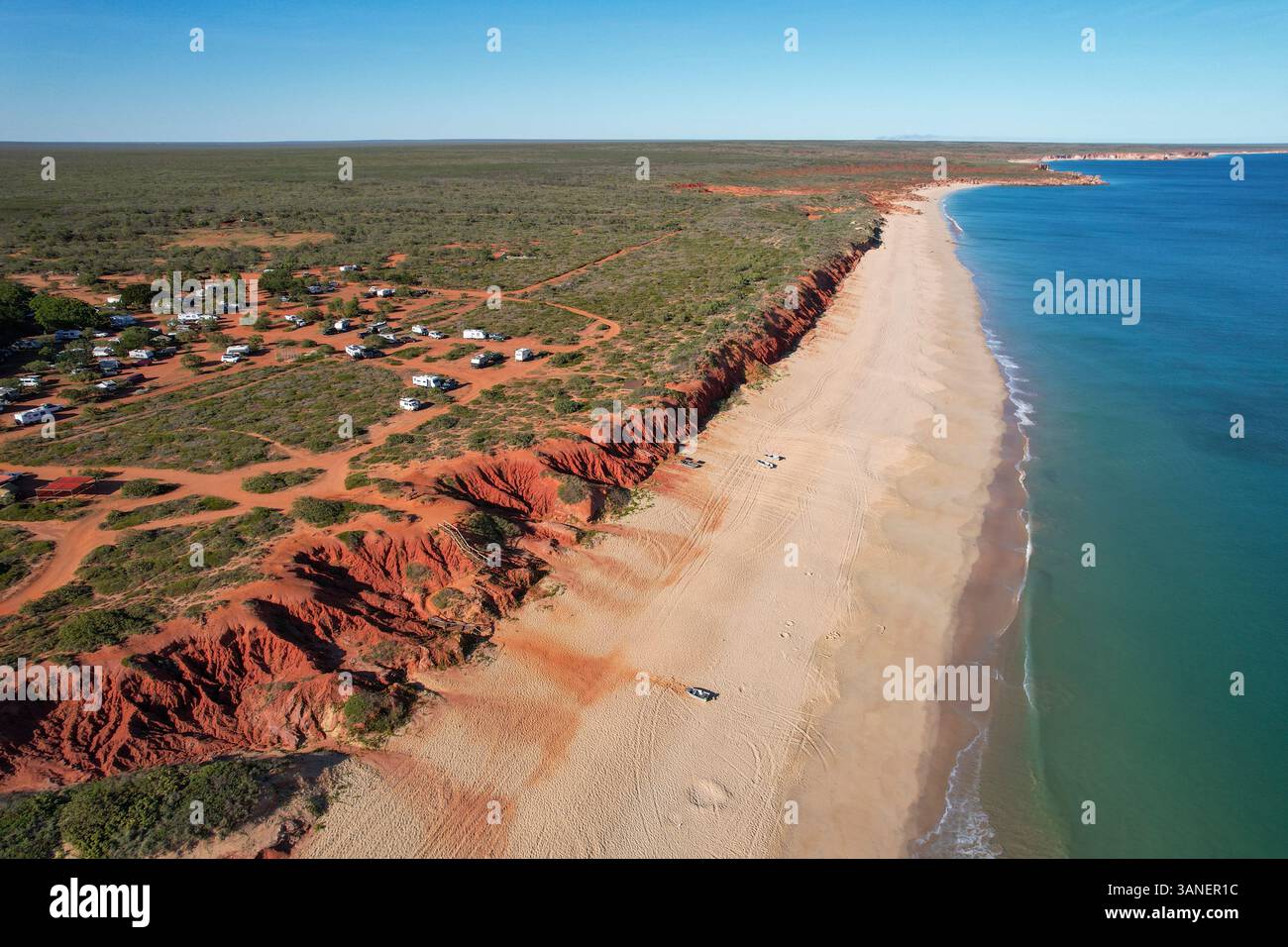 Blick aus der Vogelperspektive auf den Strand von Barn Hill, mit ockerfarbenen Klippen und einem Zinnboot am Sandstrand, Broome, Australien. Stockfoto