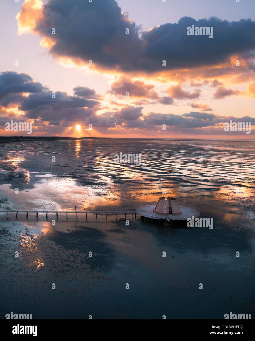 Aus der Vogelperspektive des ruhigen Sonnenaufgangs über dem ruhigen Meer mit Wolken und einem Kunstobjekt, Terschelling, Niederlande. Stockfoto