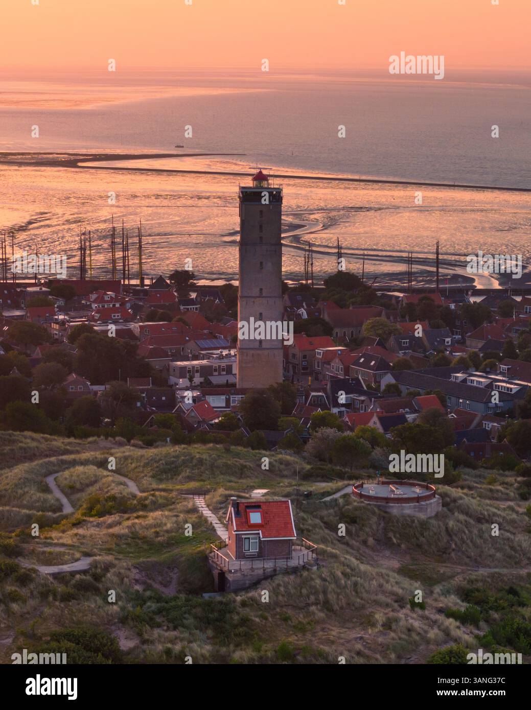 Blick aus der Vogelperspektive auf die malerische Insel Terschelling bei Sonnenuntergang mit Brandaris Leuchtturm und beschaulichem Hafen, Friesland, Niederlande. Stockfoto