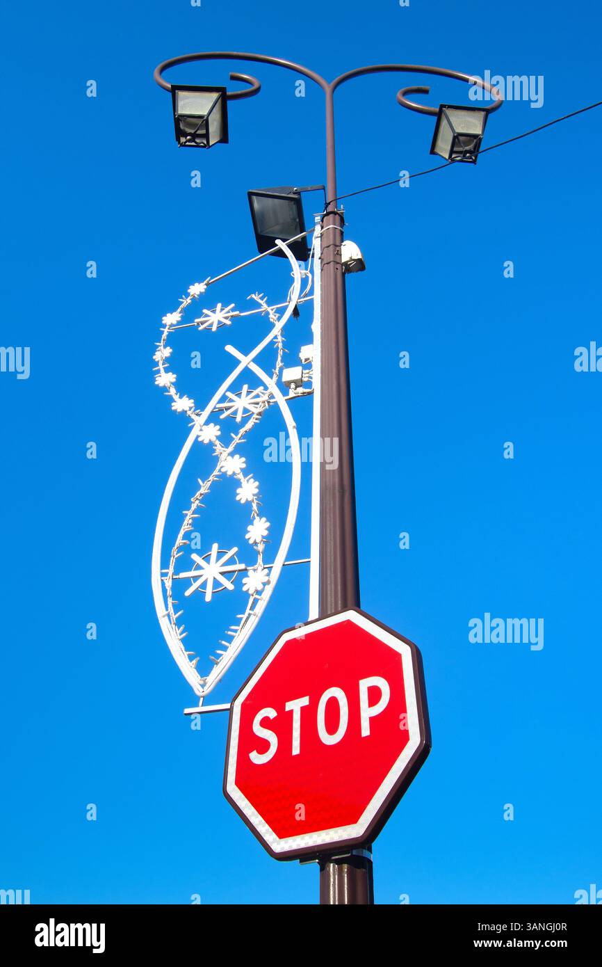 Weihnachtsdekoration an der Laterne im Stadtzentrum mit Stoppschild - Loches, Indre-et-Loire (37), Frankreich. Stockfoto