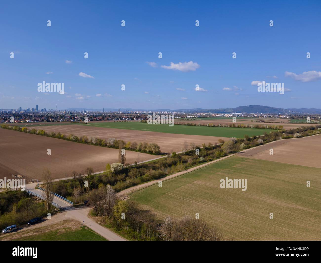 Drohnenansicht eines Bewässerungskanals mit Feldern und Bezirk 22, Donaustadt, Wien in der Ferne, Gerasdorf, Niederösterreich, Österreich. Stockfoto
