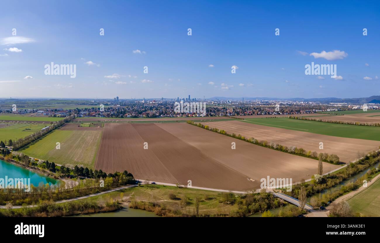 Panoramablick der Drohne auf Ackerland und Bezirk 22, Donaustadt, Wien in der Ferne, Gerasdorf, Niederösterreich, Österreich. Stockfoto