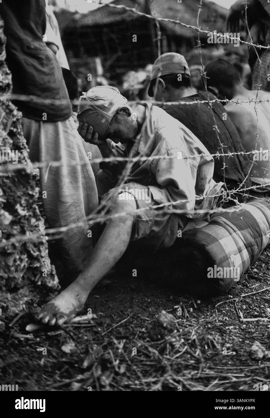 OKINAWA, JAPAN - Juni 1945 - dieser untröstliche japanische Kriegsgefangene sitzt deprimiert hinter Stacheldraht, nachdem er und etwa 306 andere gefangen genommen wurden Stockfoto
