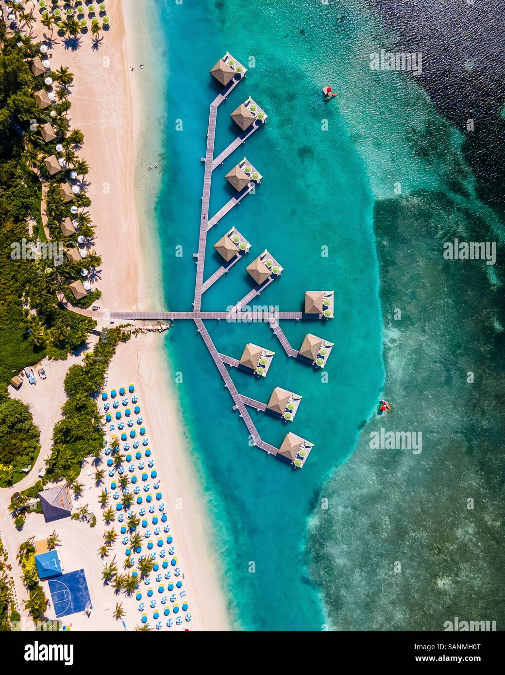 Blick aus der Vogelperspektive auf türkisfarbenes Wasser und über dem Wasser liegende Bungalows in Coco Cay, Berry Islands und den Bahamas. Stockfoto