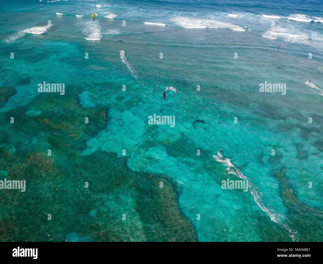 Aus der Vogelperspektive sehen Sie Kitesurfer, die Wellen über einem wunderschönen türkisfarbenen Ozean mit Korallenriffen reiten, Sosua, Dominikanische Republik. Stockfoto