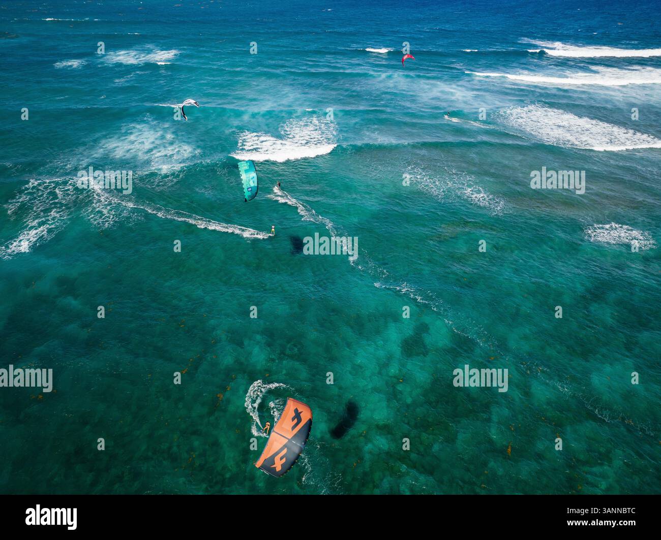 Aus der Vogelperspektive sehen Sie Kitesurfer, die an einem wunderschönen Strand entlang der Küste, Sosua, Dominikanische Republik, Wellen reiten. Stockfoto
