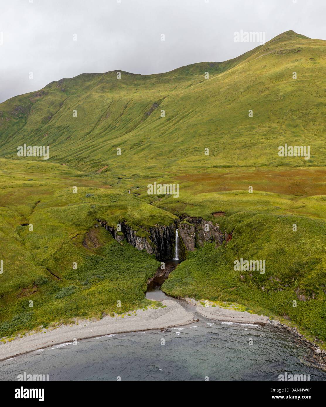 Luftaufnahme eines Wasserfalls entlang der Küste, Driftwood Bay, Unalaska Island, Alaska, USA. Stockfoto