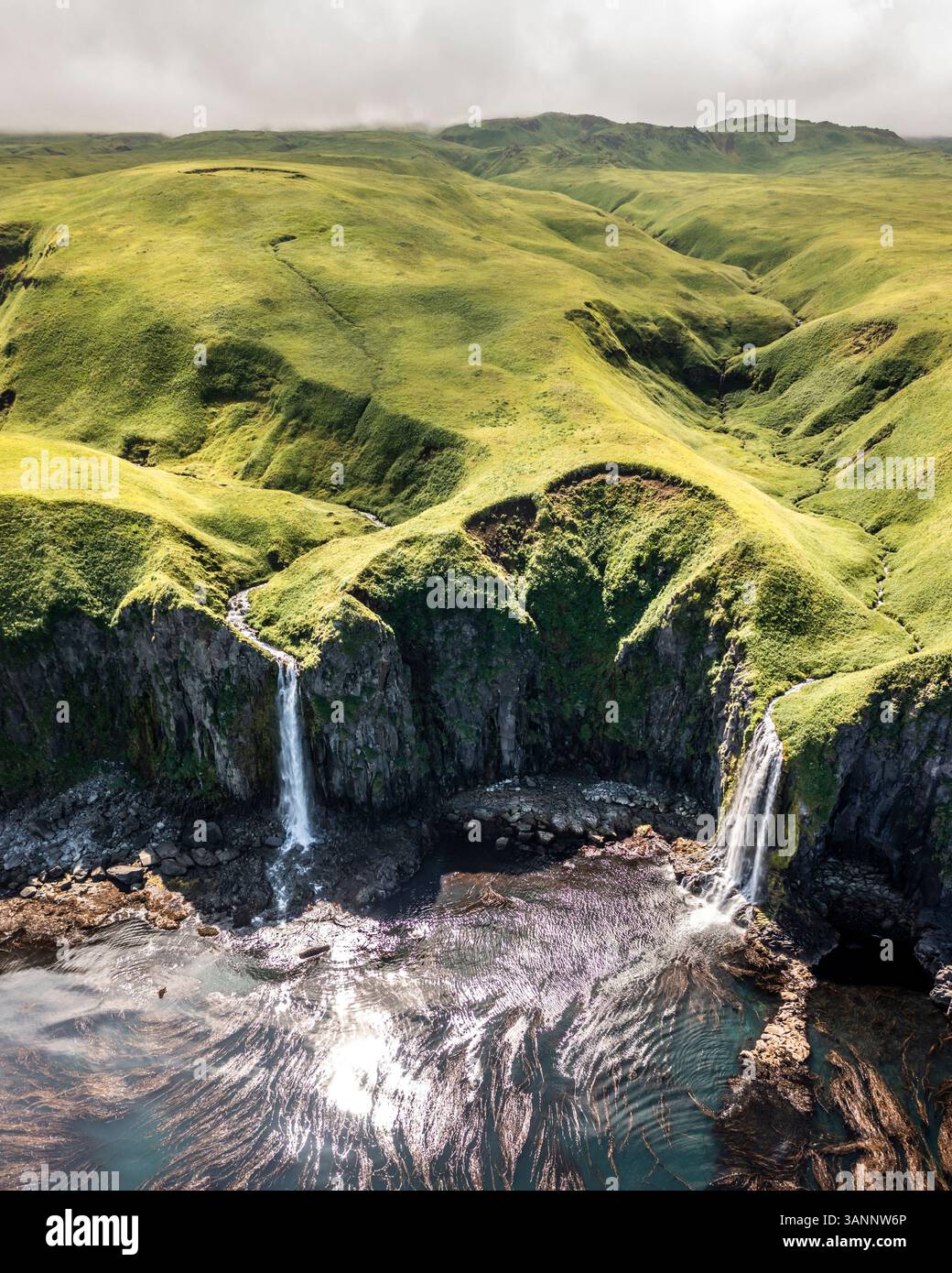 Luftaufnahme eines Wasserfalls entlang der Küste, Driftwood Bay, Unalaska Island, Alaska, USA. Stockfoto