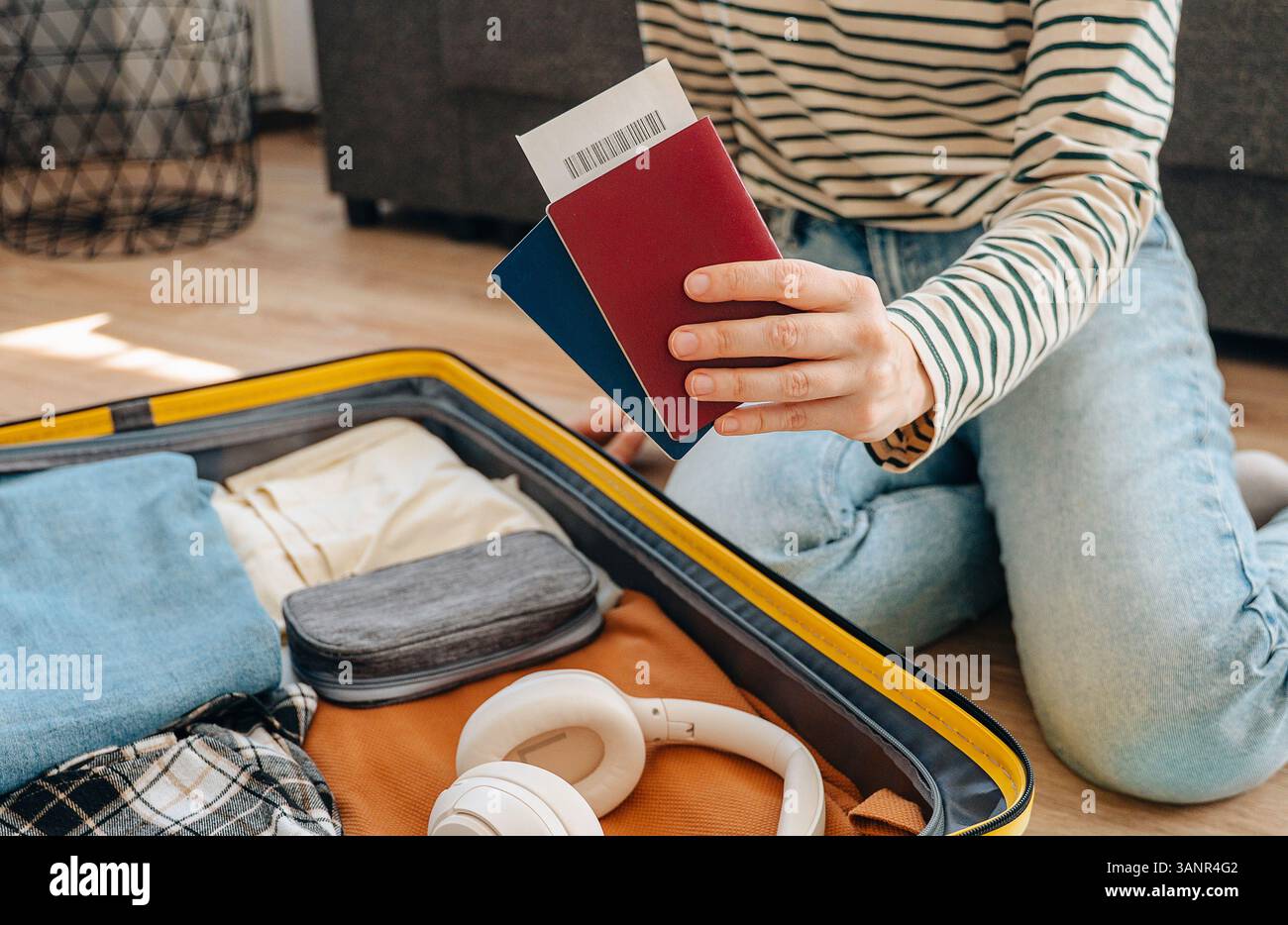 Junge Reisende, die auf dem Boden sitzt und Koffer packt, bereitet sich auf die Sommerferien vor... Stockfoto