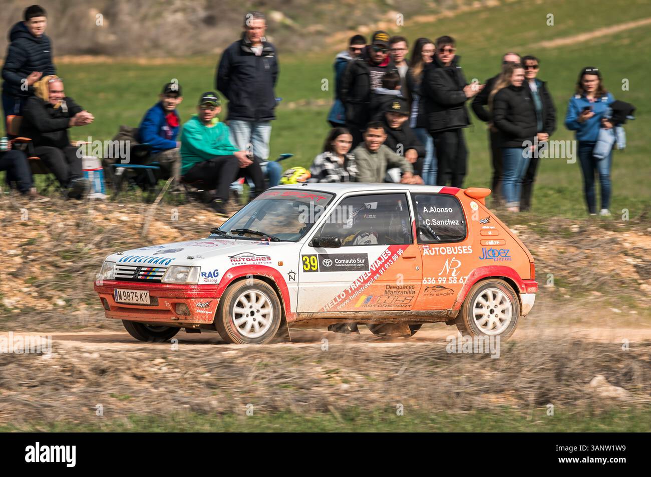 Madrid, Spanien; 15.02.2025: Der legendäre Peugeot 205 fährt während einer Rallye auf unbefestigtem Gelände, vorbei an jubelnden Menschenmengen und einer lebhaften Feier des Motorsports Stockfoto