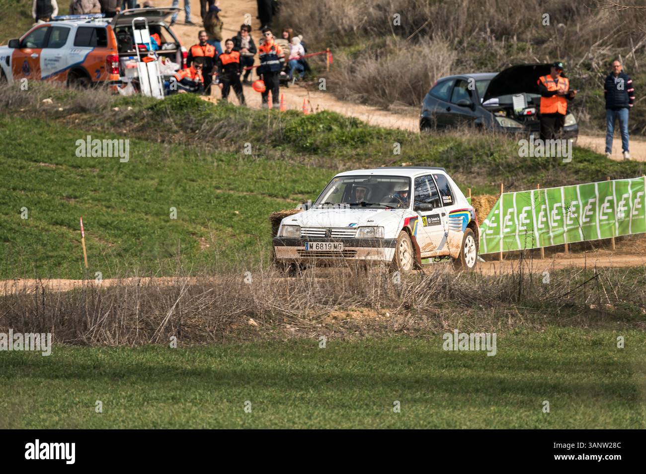 Madrid, Spanien; 15.02.2025: Der legendäre Peugeot 205 GTI brüllt während einer lebhaften Rallye-Feier unter wachsamem Einsatzpersonal auf einem Feldweg Stockfoto