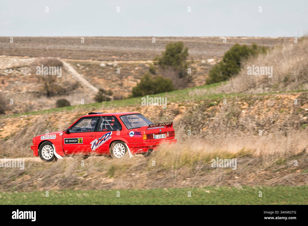 Madrid, Spanien; 15.02.2025: Klassischer roter BMW 325i E30 Rallyefahrer, der durch kurvenreiche Feldwege in einer Rallye fährt, die mit seiner Geschwindigkeit Staub aufwirft Stockfoto
