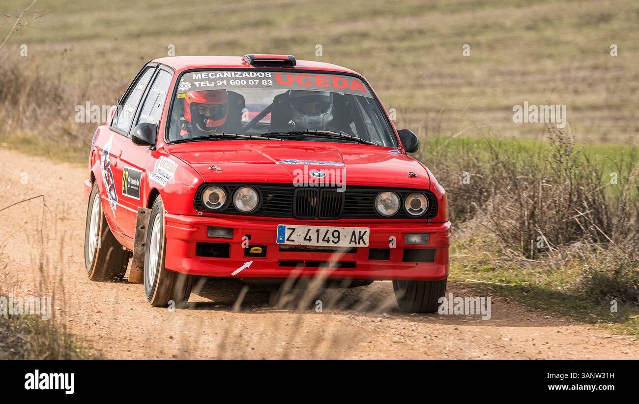 Madrid, Spanien; 15.02.2025: Klassischer roter BMW 325i E30 Rallyefahrer, der durch kurvenreiche Feldwege in einer Rallye fährt, die mit seiner Geschwindigkeit Staub aufwirft Stockfoto