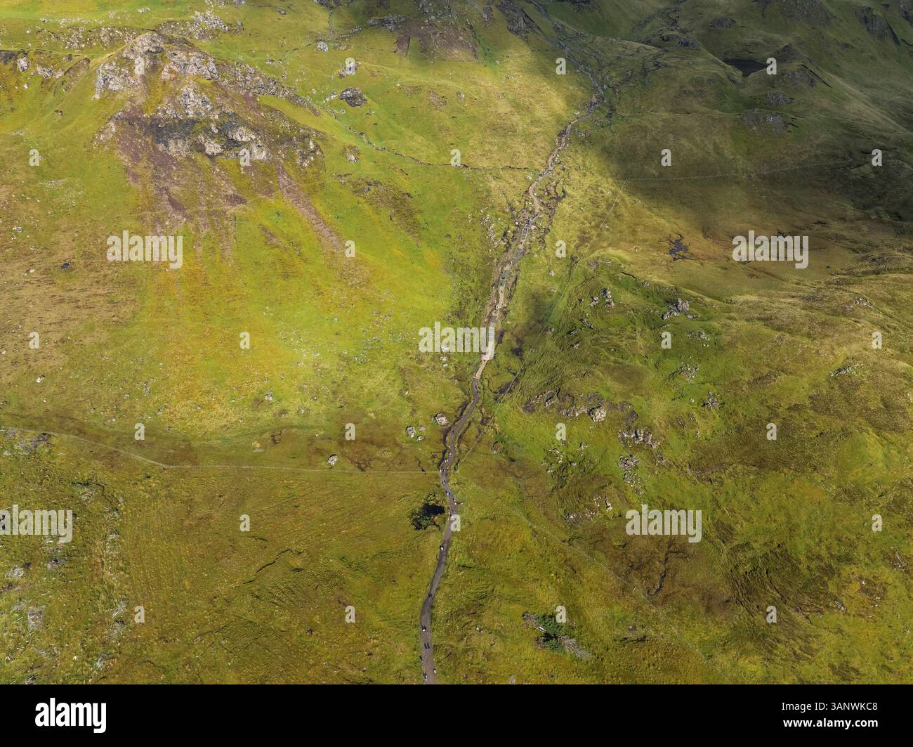 Panoramablick auf zerklüftete Hügel und einen malerischen Pfad in üppiger grüner Landschaft, Portree, Schottland. Stockfoto