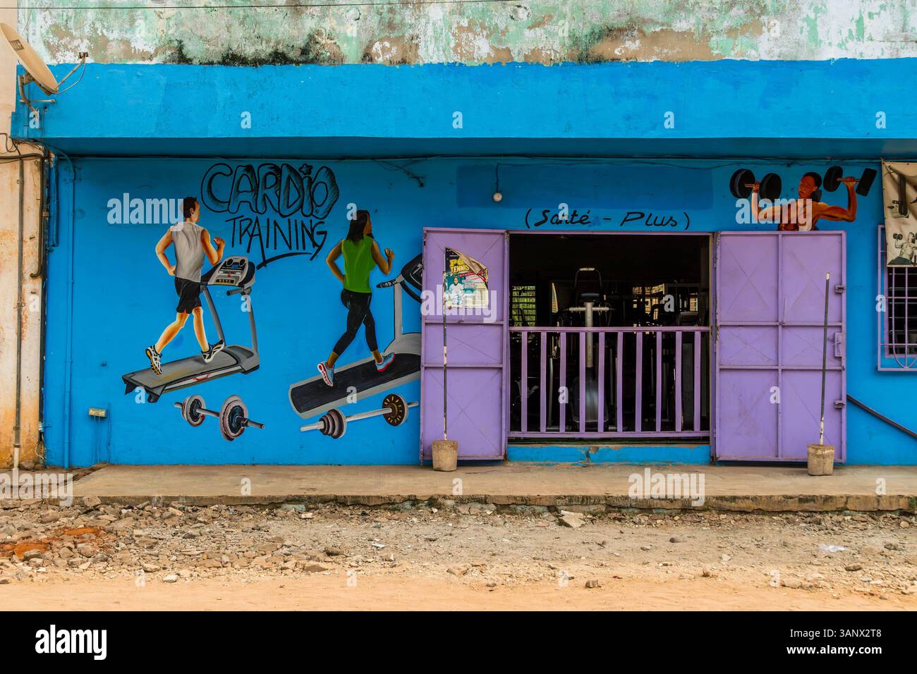 Das örtliche Fitnessstudio in Porto-Novo zeigt ein lebendiges Wandbild mit Kardio-Training und Gewichtheben, das Fitness in einem einzigartigen lokalen Stil zeigt. Stockfoto