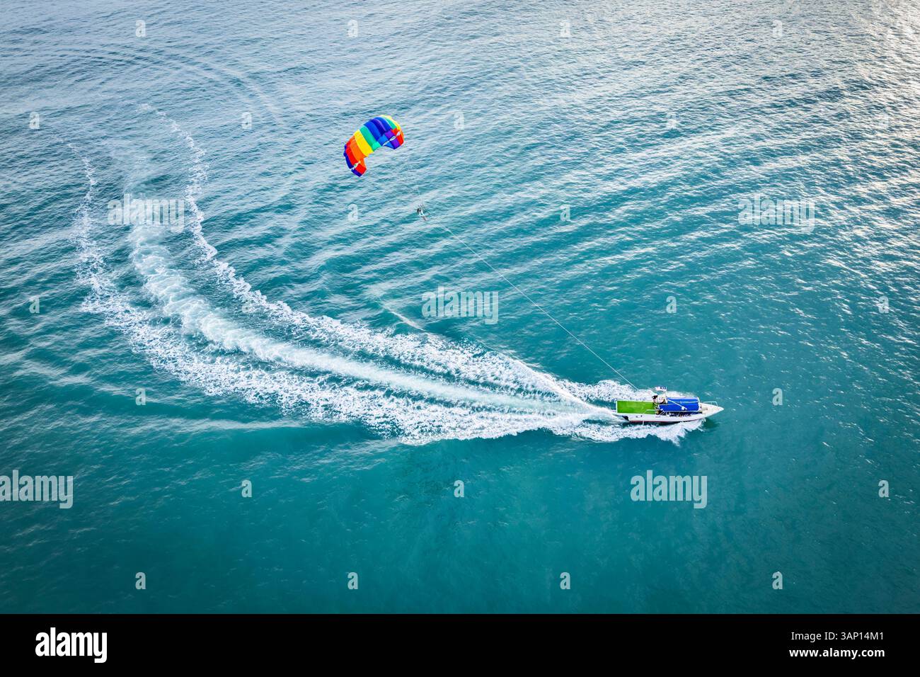 Aus der Vogelperspektive sehen Sie farbenfrohe Parasailing- und Schnellboote auf dem blauen Ozean mit klarem Himmel, Kampung Lubok Buaya, Langkawi, Malaysia. Stockfoto