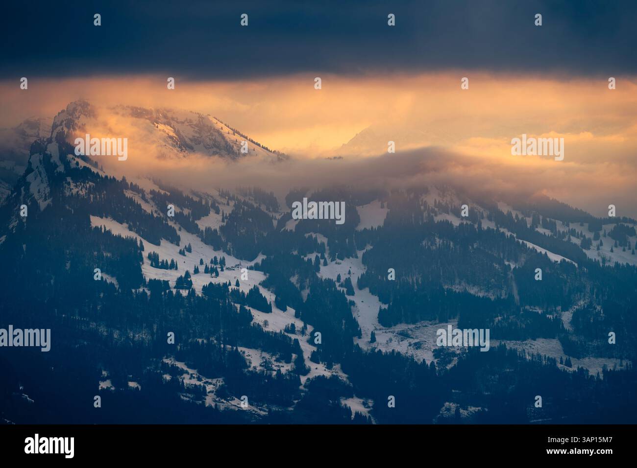 Der Sonnenuntergang beleuchtet die Wolken um die Gipfel der Glarner Alpen am Walensee Stockfoto