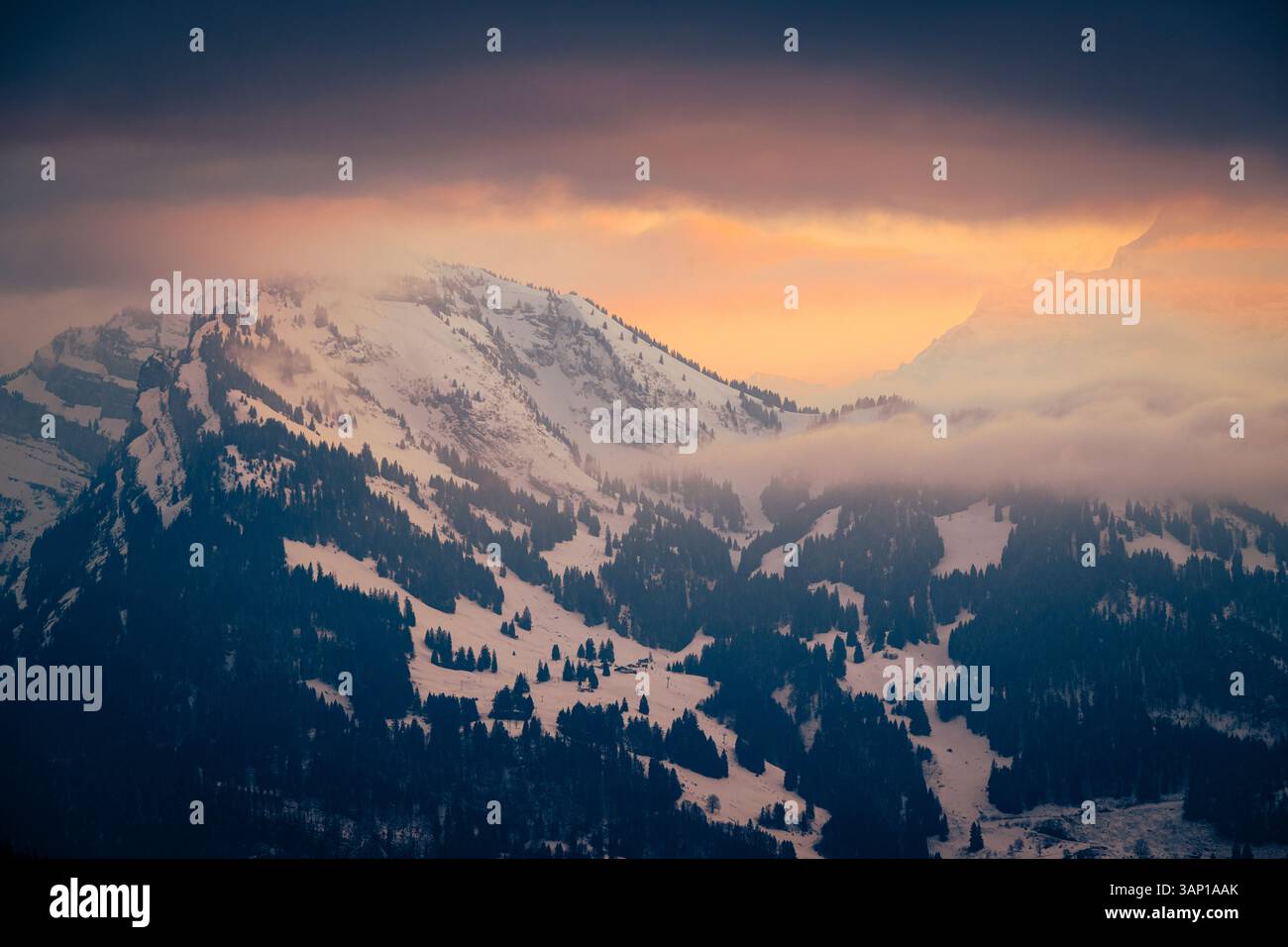 Der Sonnenuntergang beleuchtet die Wolken um die Gipfel der Glarner Alpen am Walensee Stockfoto