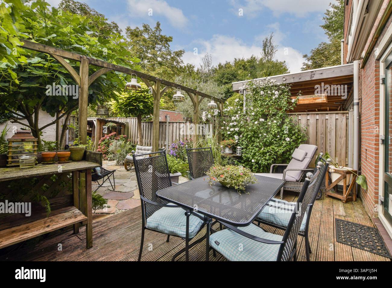 Eine ruhige Gartenterrasse mit komfortablen Möbeln, lebhaften Blumen und üppigem Grün, perfekt für Entspannung im Freien und gesellige Zusammenkünfte. Stockfoto
