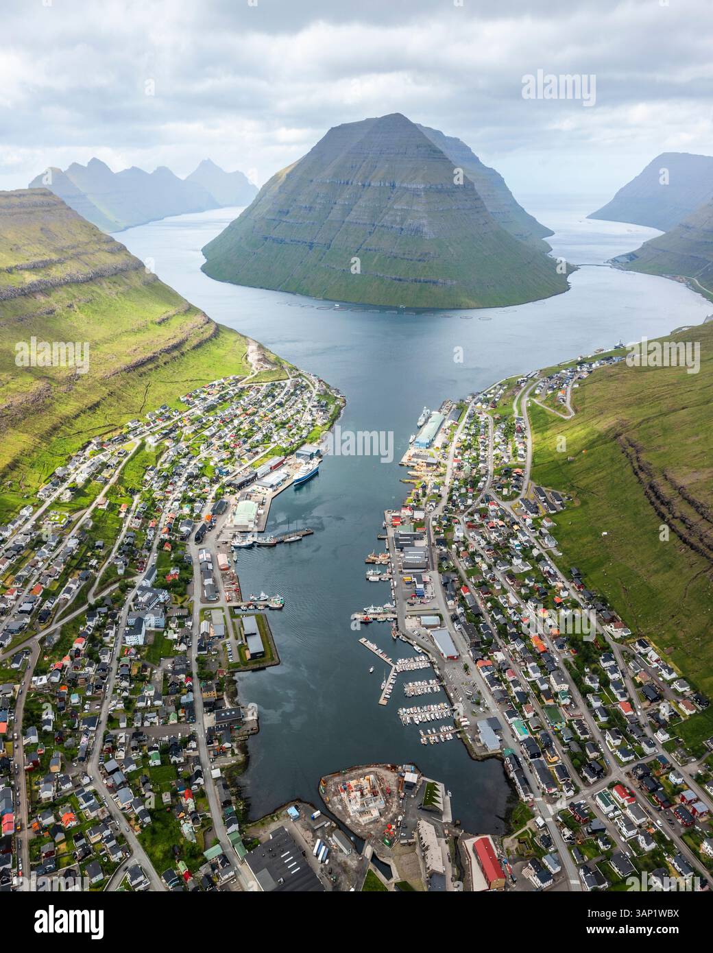 Aus der Vogelperspektive auf die malerische Stadt Klaksvik mit einem ruhigen Hafen und majestätischen Bergen, Biskupsstod, Nordoyar, Färöer Inseln. Stockfoto