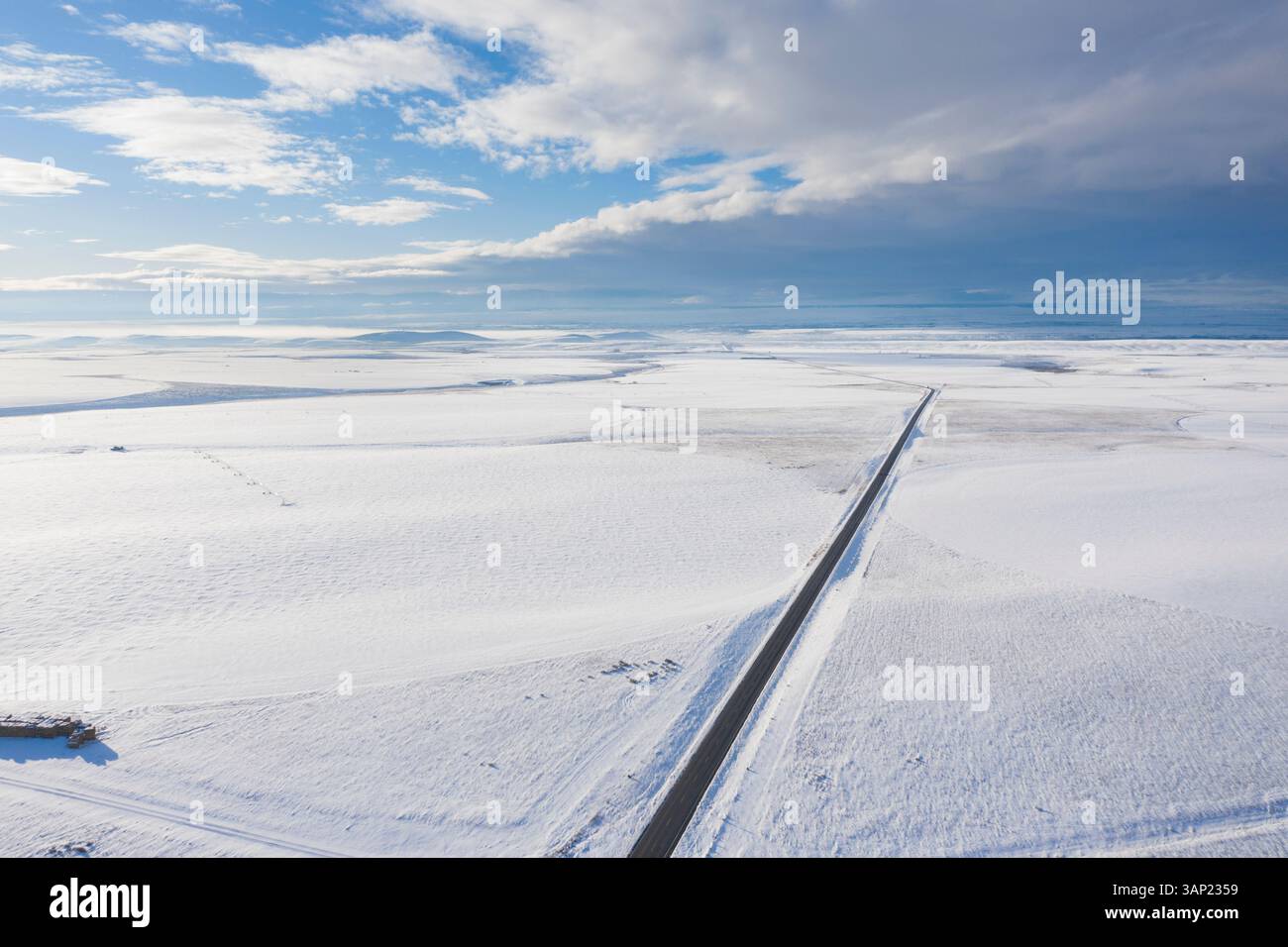 Aus der Vogelperspektive auf die schneebedeckte Straße, die sich durch ruhige Wolken schlängelt, in den ruhigen Horse Heaven Hills, Benton County, USA. Stockfoto