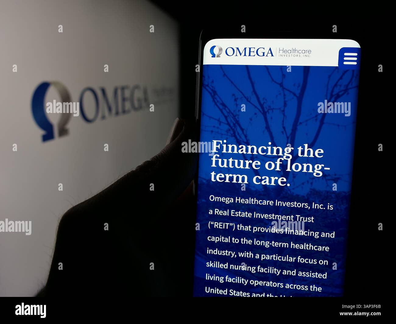 Stuttgart, Deutschland - 12.09.2024: Person, die ein Mobiltelefon hält, mit Webseite des US-amerikanischen Unternehmens Omega Healthcare Investors Inc. Auf dem Bildschirm vor dem Logo. Stockfoto