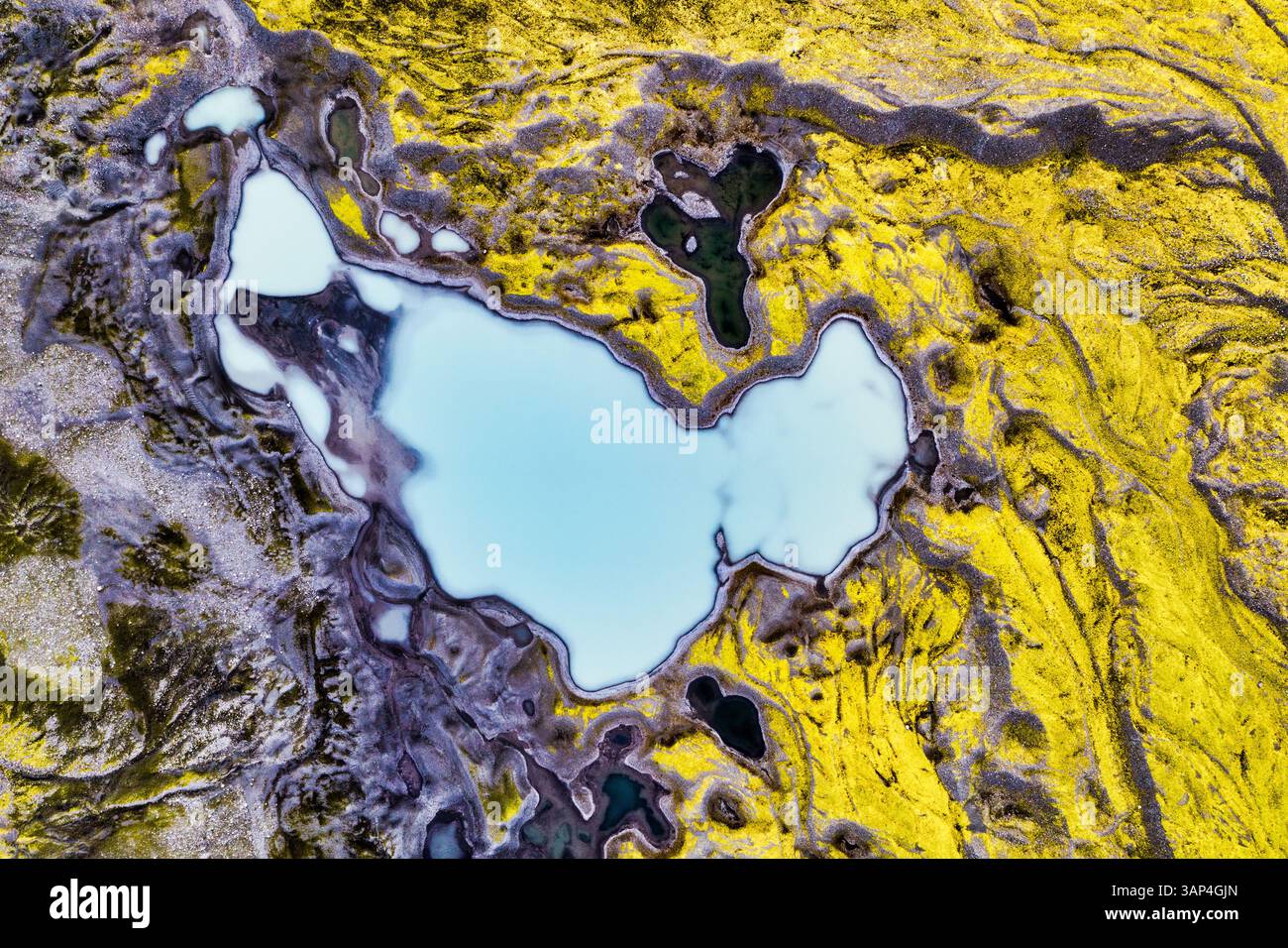 Aus der Vogelperspektive auf die farbenfrohe Landschaft rund um den blauen See, Island. Während die Seen blau sind, kommt das Gelb von den Flechten und das Grau vom Kies. Stockfoto