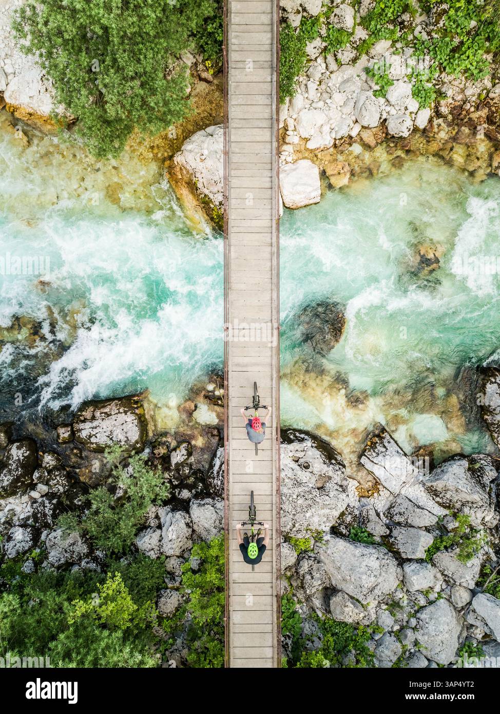 Luftaufnahme von Radfahrern auf einer hölzernen Hängebrücke am Fluss Soca, Slowenien. Stockfoto