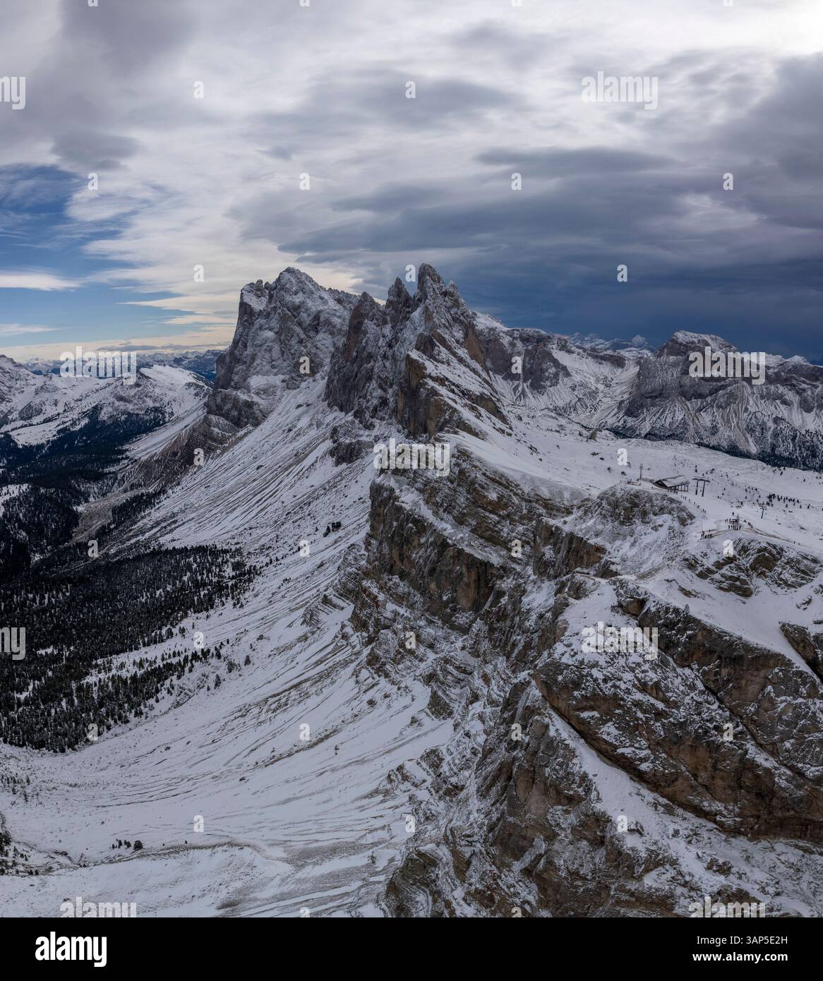 Aus der Vogelperspektive auf majestätische schneebedeckte Berge und zerklüftete Klippen unter bewölktem Himmel, St. Ulrich, Italien. Stockfoto