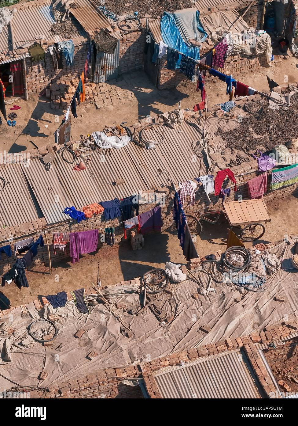 Aus der Vogelperspektive auf eine lebhafte Ziegelfabrik mit Arbeitern und traditionellen Häusern umgeben von Rikschas, Dhaka, Dhaka, Bangladesch. Stockfoto