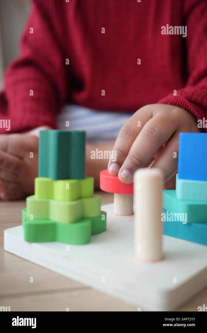 Das Kind spielt mit bunten Stapelblöcken in einer spielerischen Umgebung Stockfoto