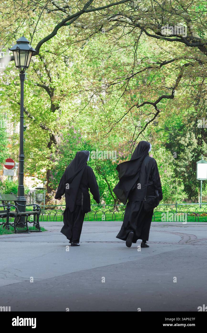 Katholisches Europa, Rückansicht zwei Nonnen, die gemeinsam durch den Planty Park im Zentrum der Stadt Krakau, Polen, Europa, laufen Stockfoto
