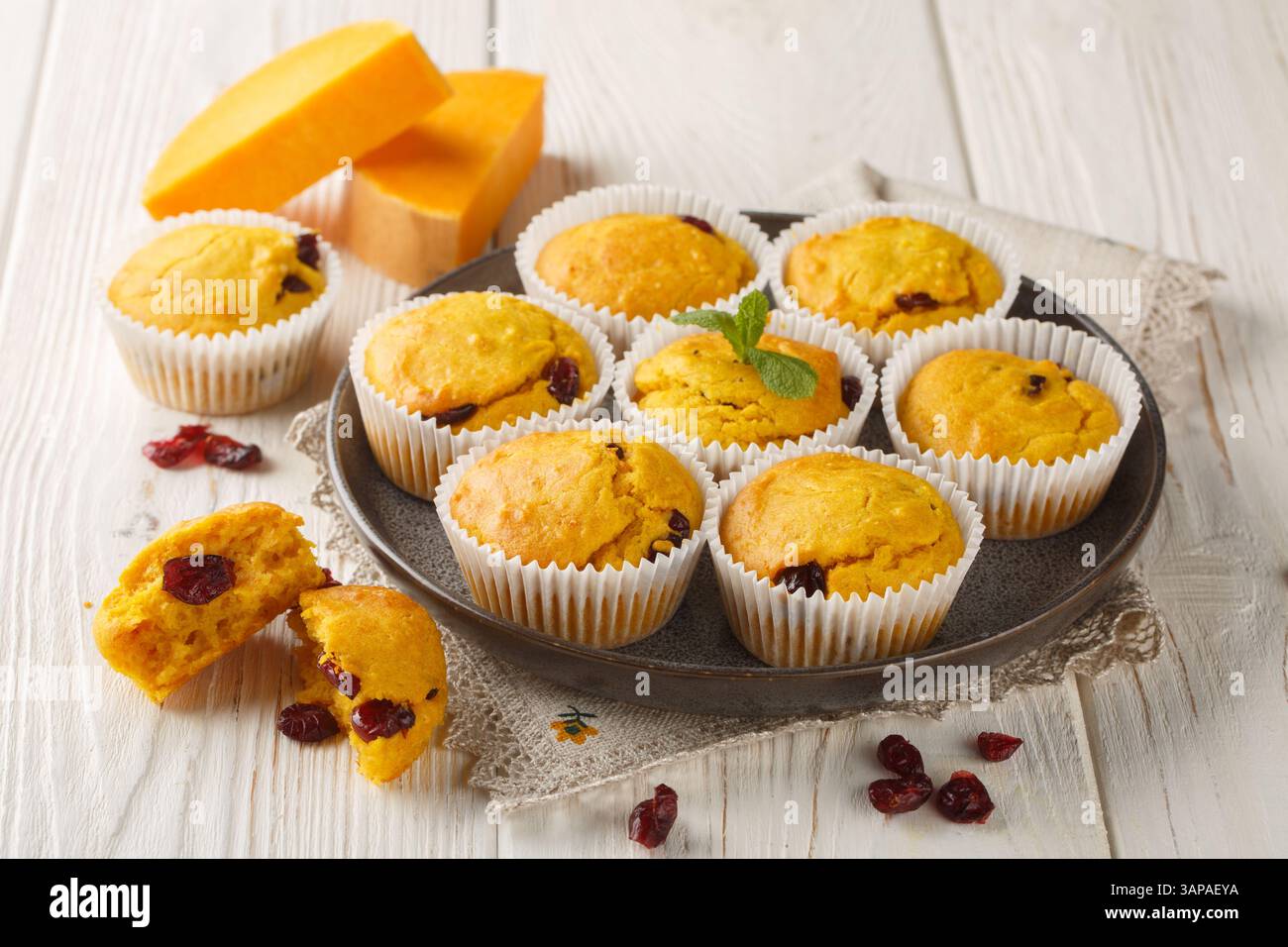Hausgemachte Muffins mit Kürbispüree, getrockneten Preiselbeeren und Gewürzen in Nahaufnahme auf einem Teller auf dem Tisch. Horizontal Stockfoto