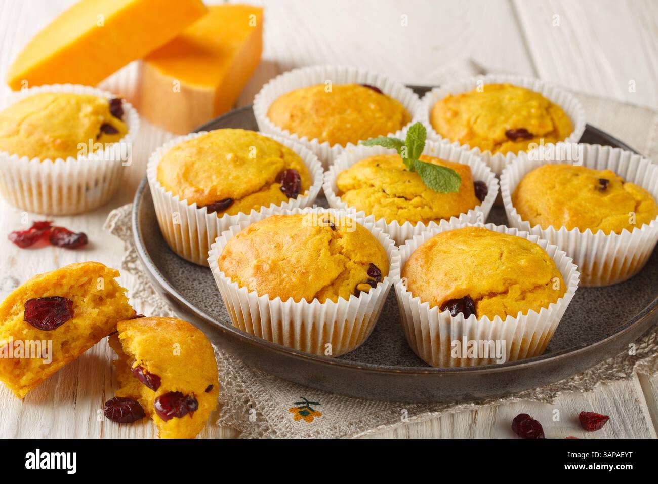Herbstmuffins mit Kürbispüree, getrockneten Preiselbeeren, Orangenschale und Gewürzen in Nahaufnahme auf einem Teller auf dem Tisch. Horizontal Stockfoto