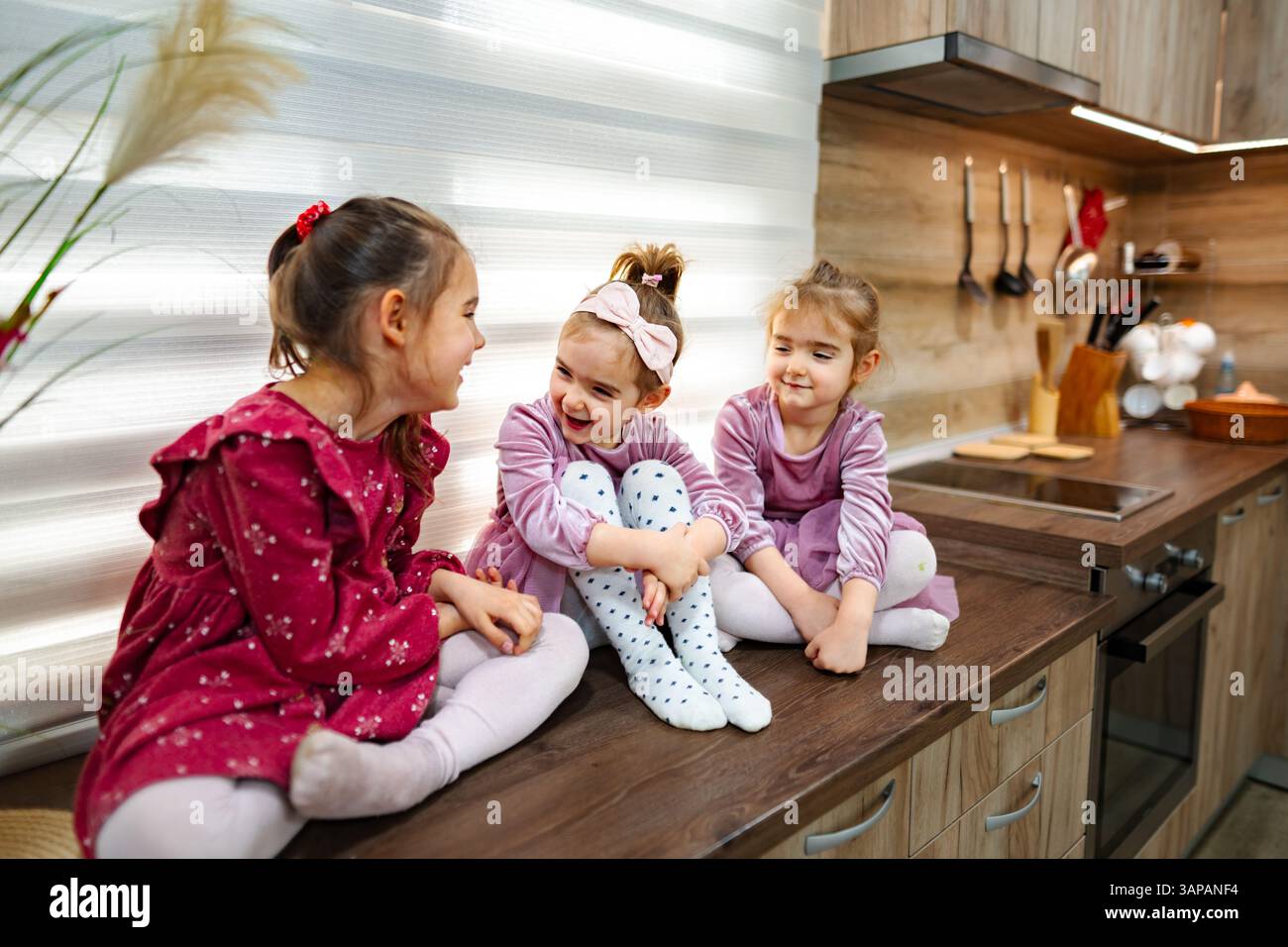 Herrliche Momente, die an einem sonnigen Nachmittag in einer gemütlichen, hellen Küche unter drei Schwestern geteilt werden Stockfoto