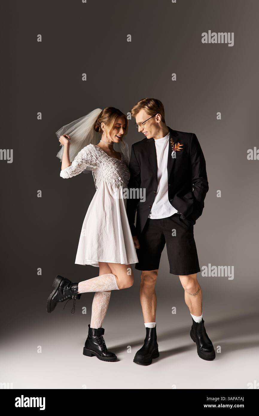 Ein Paar zeigt fröhlich ihre unkonventionelle Hochzeitskleidung in einem Frühlingsumfeld zusammen. Stockfoto