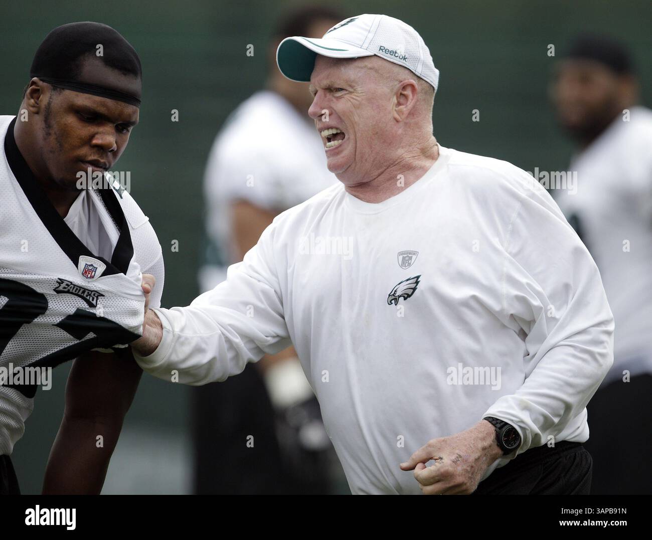29. Juli 2011 – Bethlehem, PA, USA – Philadelphia Eagles Defensive Line Coach Jim Washburn, rechts, greift Brodrick Bunkley, links, wie er will, dass seine Spieler das Trikot während eines Trainingslagers an der Lehigh University in Bethlehem, Pennsylvania, am Freitag, 29. Juli 2011 schnappen. (Bild: © David Maialetti/Philadelphia Daily News/MCT/ZUMAPRESS.com) Stockfoto
