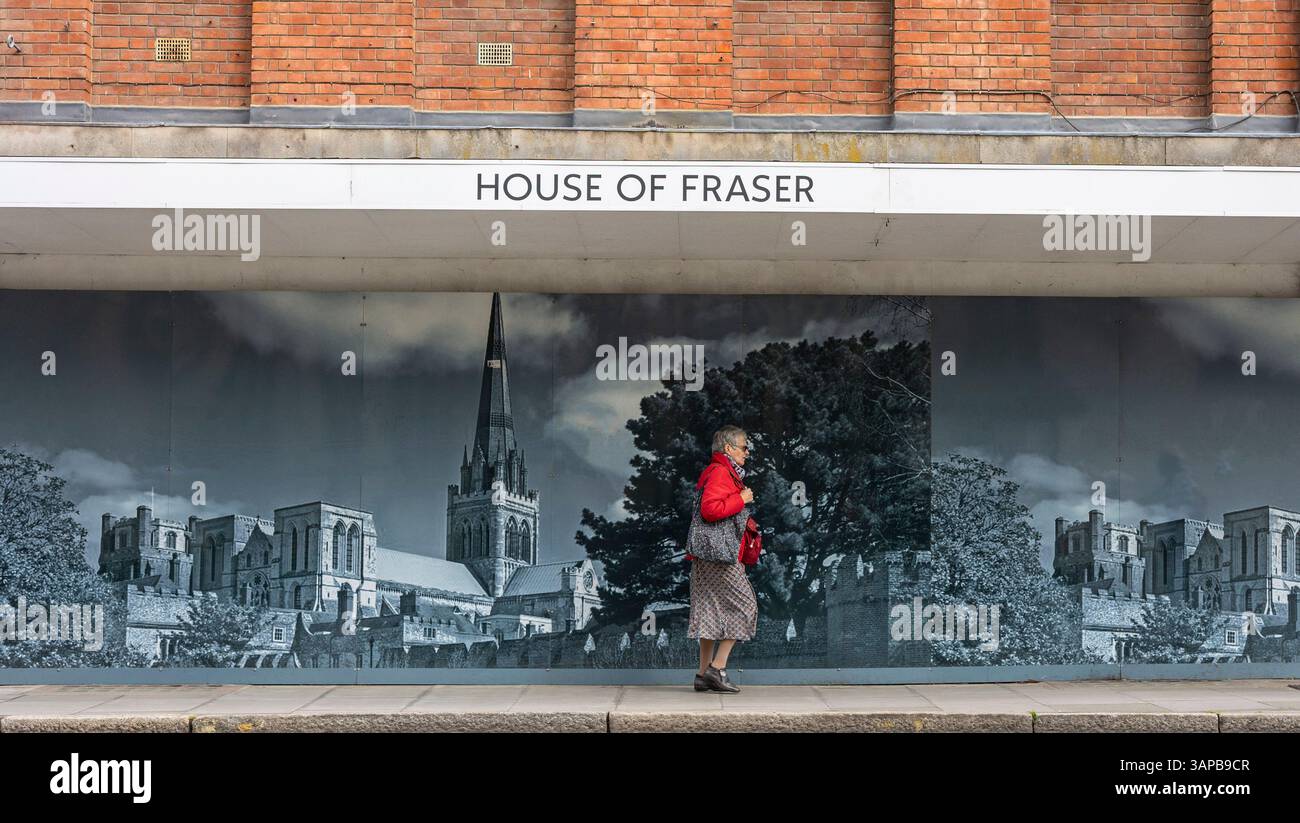 Das heute stillgelegte Kaufhaus House of Fraser. Eine Frau geht an der Fotomontage vorbei, die ein großes Fenster bedeckt. Chichester, West Sussex, Großbritannien. Stockfoto