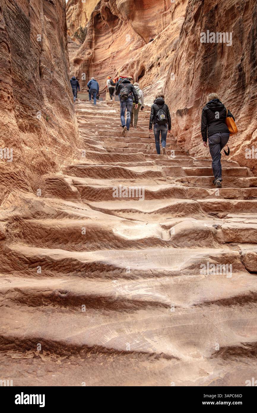 Touristen, die abgenutzte Steintreppen innerhalb des Siq in petra, jordanien, aufsteigen Stockfoto