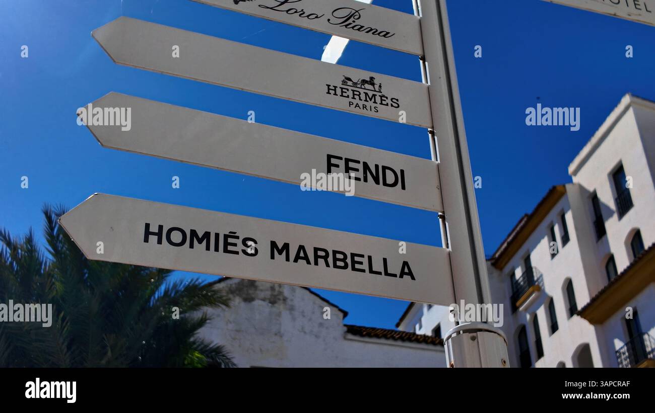 Weißer Wegweiser zu den Geschäften Loro Piana, Hermes Paris, Fendi und Homies Marbella in Marbella, Spanien - MARBELLA, SPANIEN - 30. MÄRZ 2025 Stockfoto