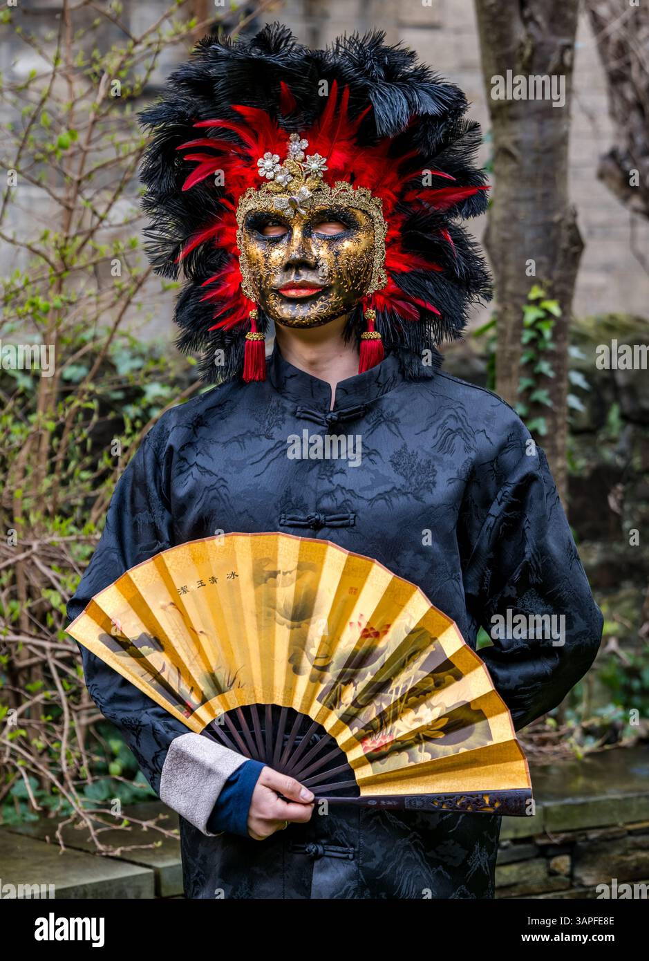 Ein Mann mit chinesischem Kostüm und Fan und venezianischer Maske für das Granatapfelfestival, Scottish Storytelling Centre, Edinburgh, Schottland, Großbritannien Stockfoto