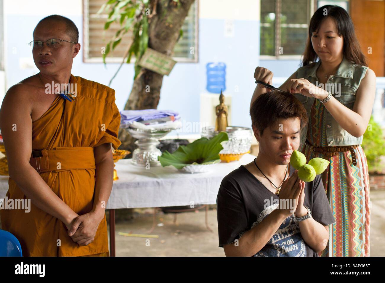 28. Juni 2011 – Chiang Mai, Chiang Mai, Thailand – Ein Familienmitglied schneidet einem Mann, der im Wat Phrathat Doi Saket, einem großen Tempelkomplex in Chiang Mai, Thailand, als buddhistischer Mönch geweiht wurde, eine Haarlocke aus dem Kopf. Der Tempel von Doi Saket soll im Jahr 1112 erbaut worden sein, wurde seither aber mehrmals renoviert. Die meisten thailändischen Männchen betreten den buddhistischen Klerus, den Sangha genannt, mindestens einmal in ihrem Leben. Ihr Aufenthalt im Kloster kann je nach Mann nur eine Woche oder ein lebenslanges Kommitment sein. Foto: Jack Kurtz / ZUMA Press (Foto: © Jack Kurtz/Z Stockfoto
