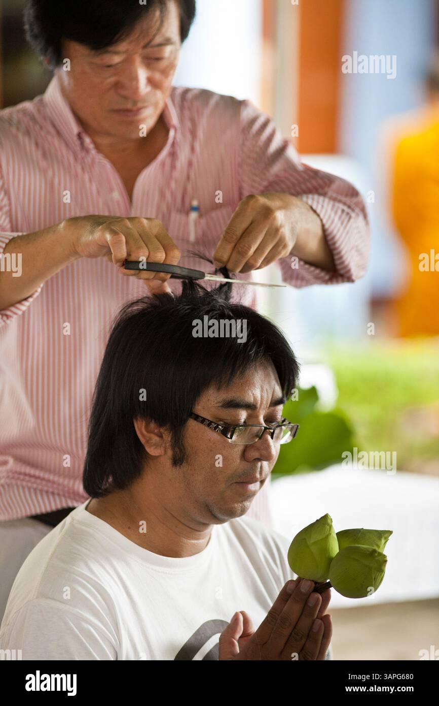 28. Juni 2011 – Chiang Mai, Chiang Mai, Thailand – Ein Familienmitglied schneidet einem Mann, der im Wat Phrathat Doi Saket, einem großen Tempelkomplex in Chiang Mai, Thailand, als buddhistischer Mönch geweiht wurde, eine Haarlocke aus dem Kopf. Der Tempel von Doi Saket soll im Jahr 1112 erbaut worden sein, wurde seither aber mehrmals renoviert. Die meisten thailändischen Männchen betreten den buddhistischen Klerus, den Sangha genannt, mindestens einmal in ihrem Leben. Ihr Aufenthalt im Kloster kann je nach Mann nur eine Woche oder ein lebenslanges Kommitment sein. Foto: Jack Kurtz / ZUMA Press (Foto: © Jack Kurtz/Z Stockfoto